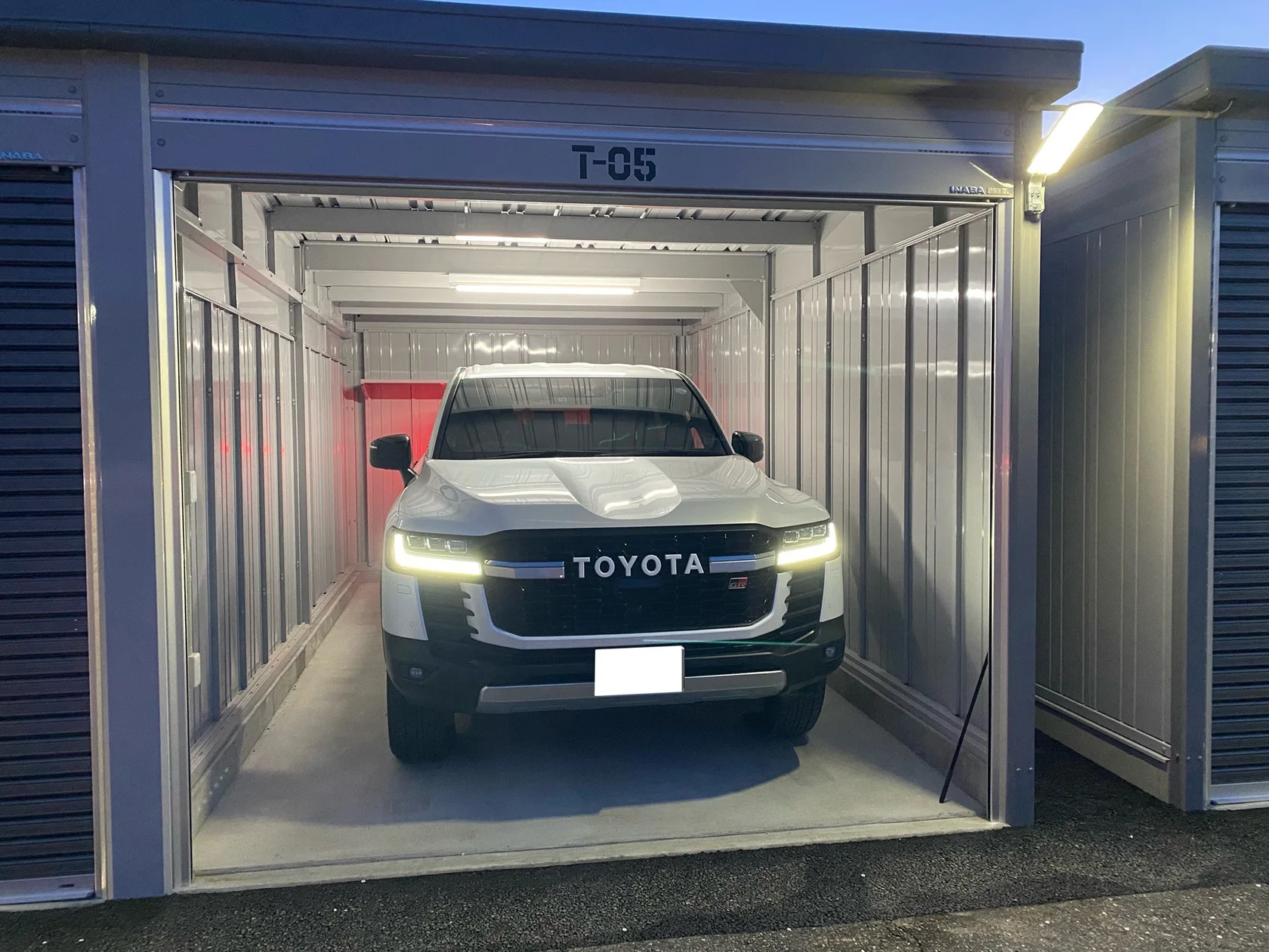 シャッターを開けたT-05区画に駐車された白いSUV